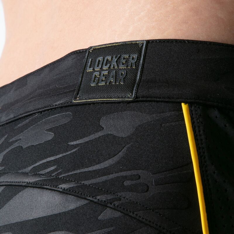 Gros plan sur le camouflage noir, le passepoil jaune et le logo Locker Gear du short