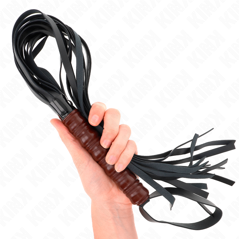 Main tenant le manche à reliefs du martinet KINK, avec les lanières noires repliées