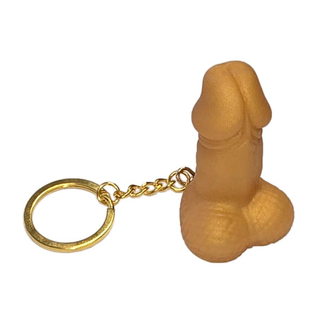 Goldfarbener Penis-Schlüsselanhänger mit Kette und Ring vor weißem Hintergrund.