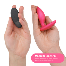 Télécommande noire et plug Ditto+ rose présentés dans deux mains.