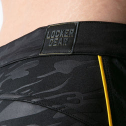 Gros plan sur le camouflage noir, le passepoil jaune et le logo Locker Gear du short